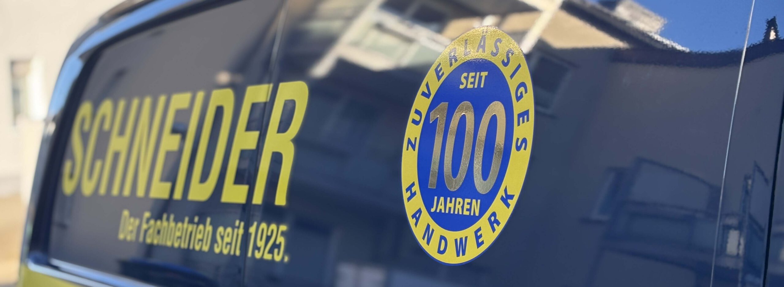 Schneider Heiztechnik Fahrzeug Schneider Heiztechnik, Firmenfahrzeug schräge Seitenansicht mit dem Jubiläumslogo